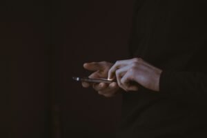 silhouette photo of a person holding the phone in the dark